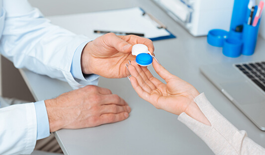 Doctor passing contact lenses during contact lens eye exam